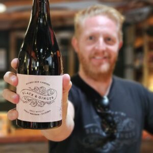 Darcy holding a bottle of The Virginia merlot, arm outstretched