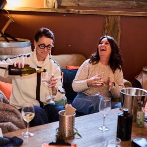 Guests laughing and enjoying a bottle of bubbles at the wine shed