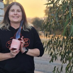Lucy holding a bottle of Lucy's Rose at Sunset at Hounds Run